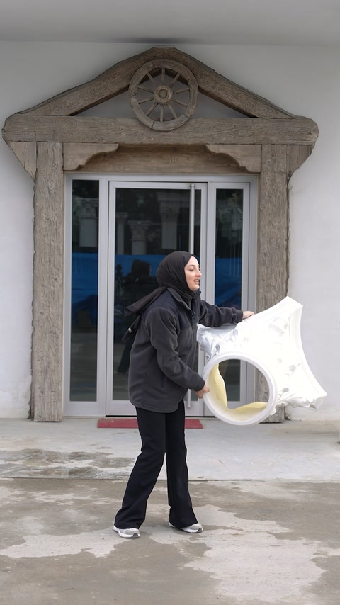 Woman carries a large sculpted decorative piece with one hand.