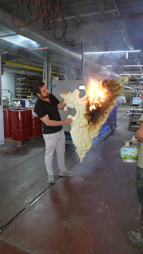 Large sculpted relief undergoes direct flame exposure inside the workshop.