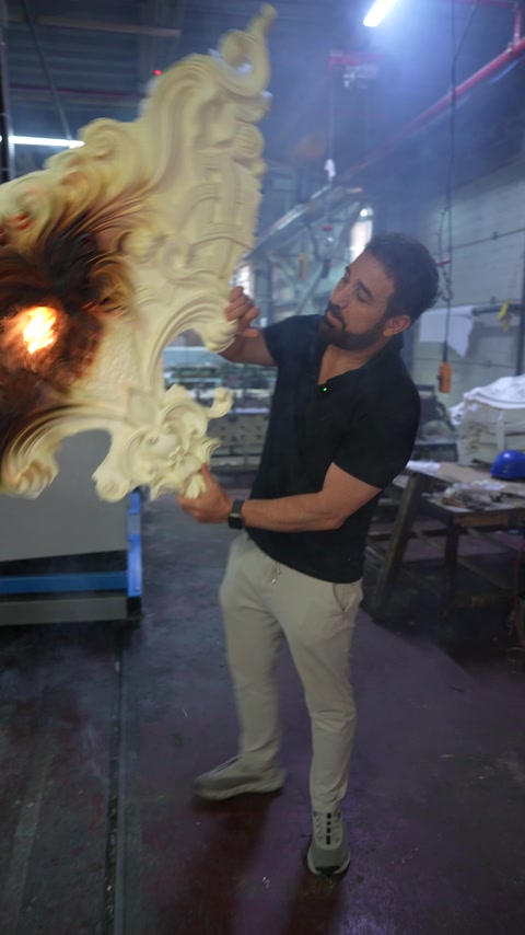 Worker inspects the ornate relief closely during direct flame testing.