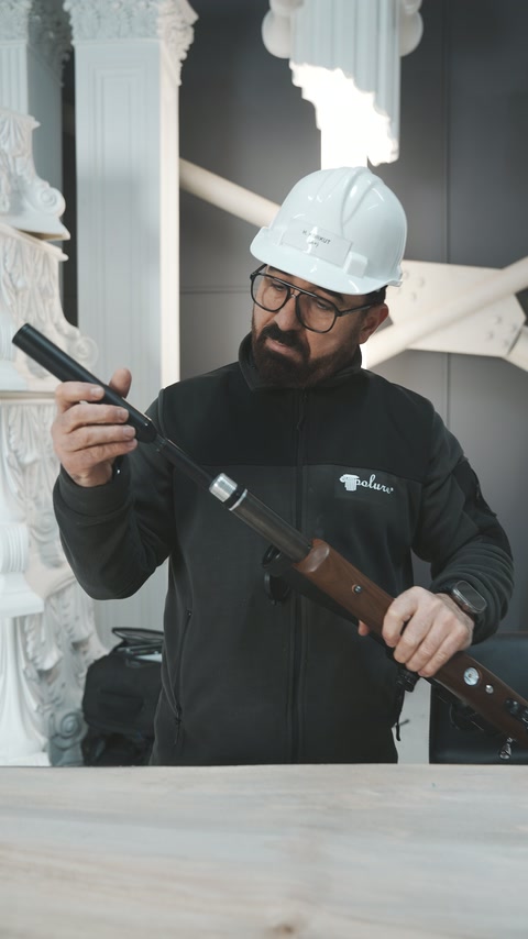 The worker examines the opened rifle mechanism inside the showroom.