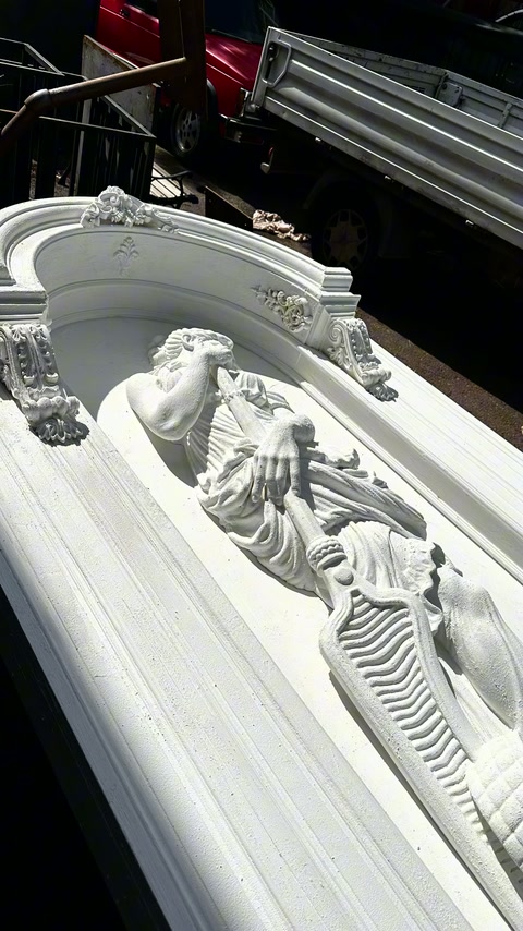 Un pannello ad arco separato mostra una figura alata sdraiata e una cornice modanata