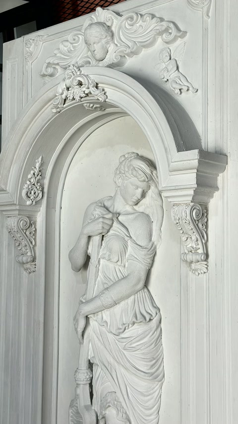 Il dettaglio ravvicinato mostra una figura drappeggiata all’interno di una nicchia ad arco ornata