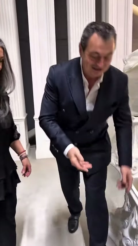 Showroom ziyaretçisi, süslü kaide önünde yerdeki ürünü almak için eğiliyor