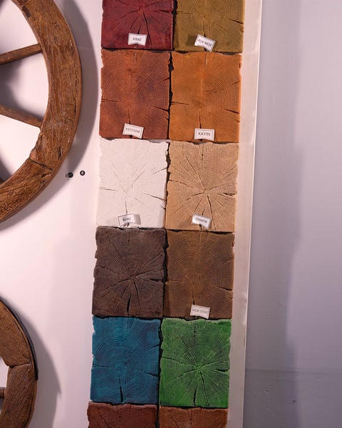 Campioni colorati di sezioni effetto legno e un elemento a forma di ruota appesi alla parete