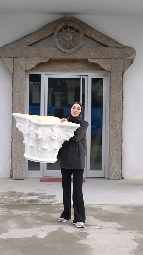 Un capitello per colonna bianco in poliuretano decorato con motivi vegetali viene presentato da vicino