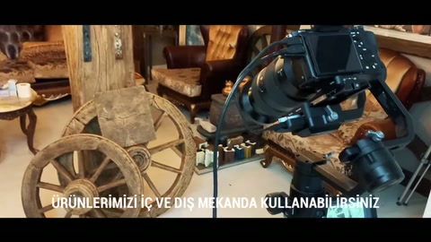 Decorative wheels and beams are arranged behind the camera in the workshop.