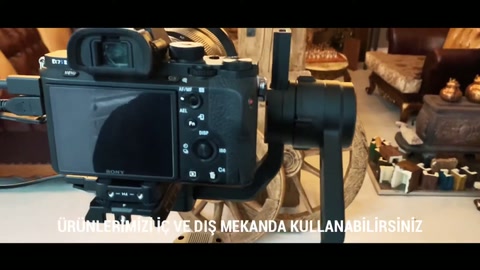 Wood-textured wheels and beams are positioned next to the camera equipment.