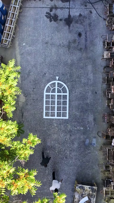 Una griglia di finestra ad arco giace centrata sul pavimento del cortile del laboratorio