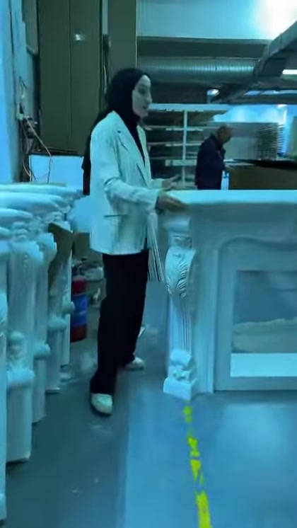 Il presentatore mostra l'ampia apertura di un modello di camino con cornice semplice