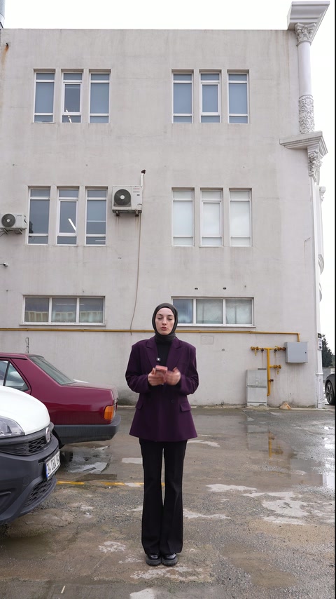 Sunucu, süslemesiz çok katlı yapının önünde uygulama alanını tanıtıyor
