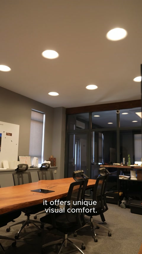 Illuminazioni amorfiche a soffitto si estendono sopra il lungo tavolo della sala riunioni