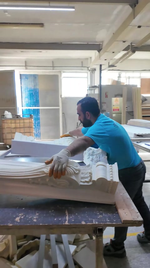 Un artigiano preme un elemento angolare intagliato sulla struttura per fissarlo
