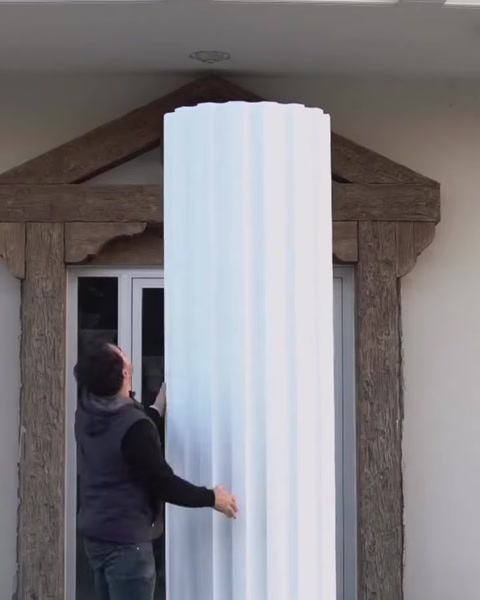 Man wraps fluted panel around column shaft on building.