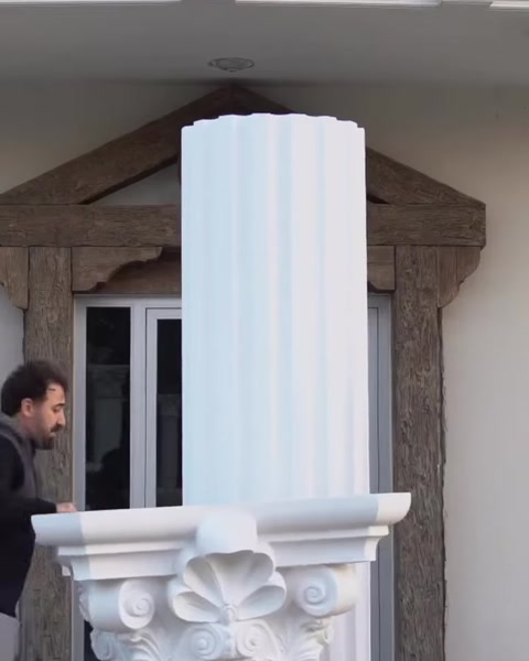 Installer positions capital piece near column top on facade.
