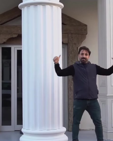 Man poses beside completed polyurethane column on building.