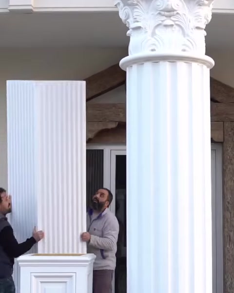 Two men attach fluted panel to second column shaft.