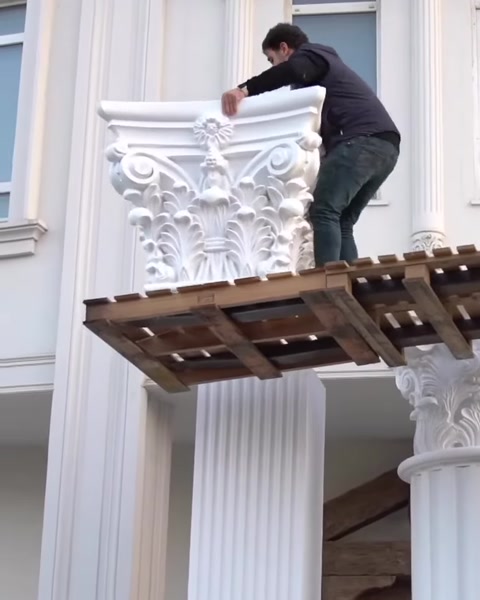 Installer attaches decorative capital to top of column.
