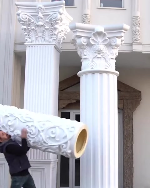 Worker carries hollow polyurethane capital piece on platform.