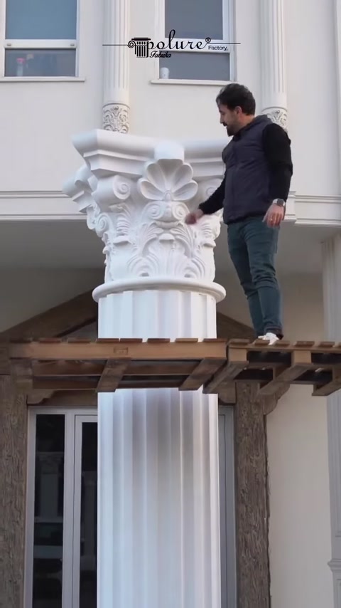 Installer fits ornate capital atop column shaft outdoors.