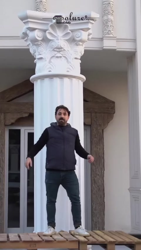 Finished fluted column stands beside entrance columns.