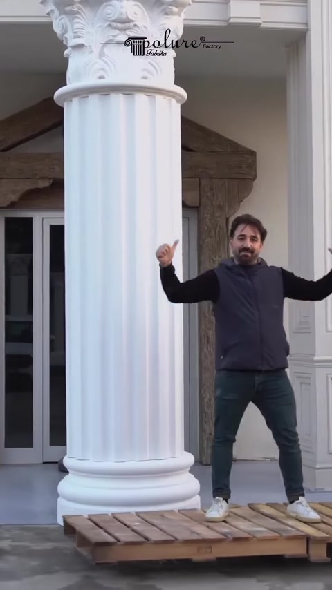 Man poses beside completed polyurethane column on building.