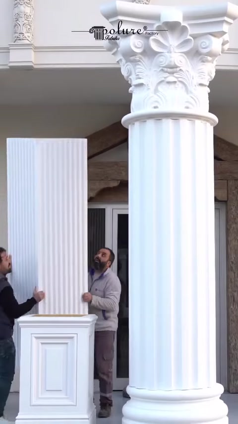 Two men attach fluted panel to second column shaft.