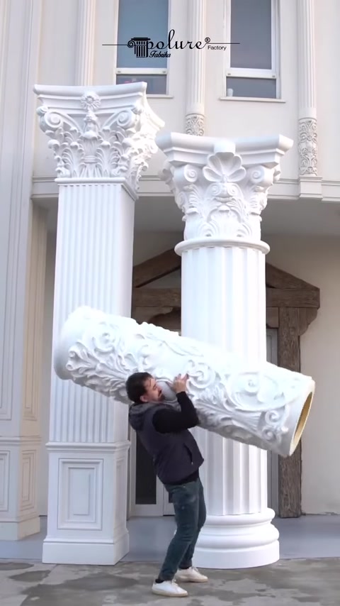 Worker lifts ornate capital piece toward column top.