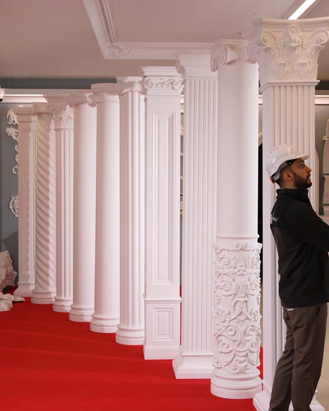 Una fila di colonne in poliuretano ornate delimita un corridoio con moquette rossa.