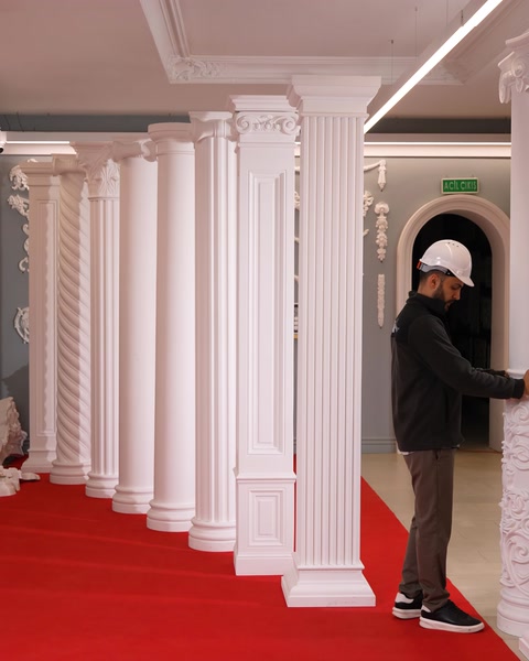 L'operaio inclina una grande colonna decorativa durante la manipolazione in sala espositiva.