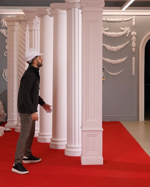 L'operaio si trova tra le colonne vicino a un muro decorato con ghirlande floreali.