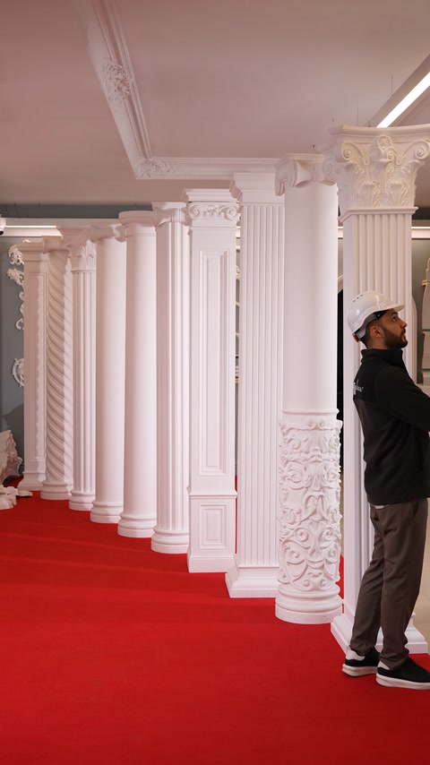 Row of ornate polyurethane columns lines a red carpet corridor.