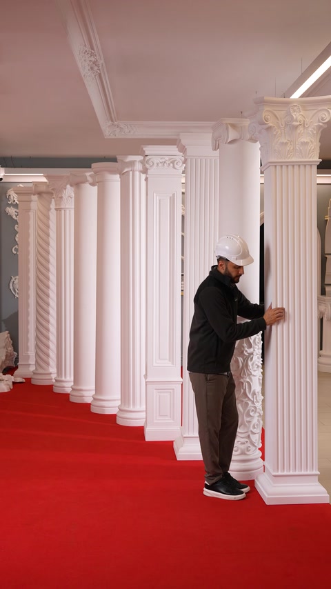 Worker inspects a carved polyurethane column with detailed capital design.