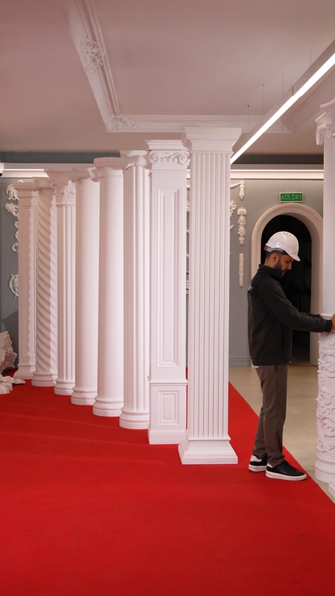 Worker tilts a large decorative column during handling in the showroom.