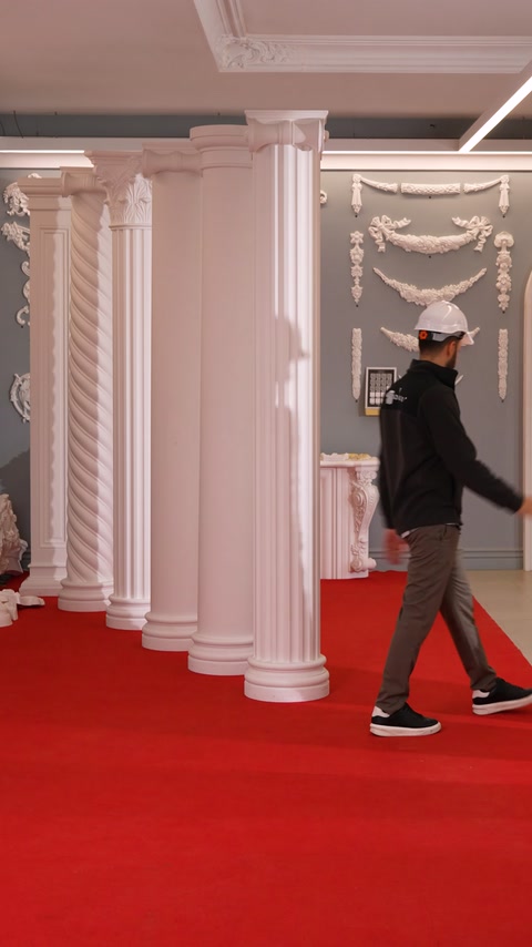 Worker walks past columns toward a room with relief wall decor.