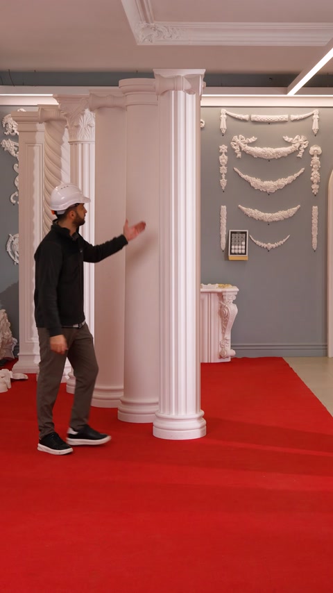 Craftsman gestures near a column beside an ornate fireplace surround.