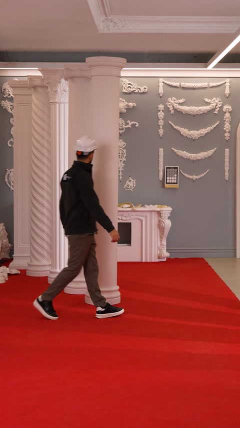 Worker walks across the room featuring fireplace and relief wall moldings.