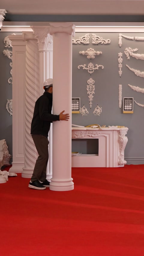 Fluted column stands beside a fireplace mantel with relief wall decor.