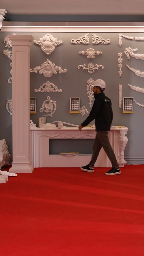 Worker walks away from fireplace display featuring fluted column decor.