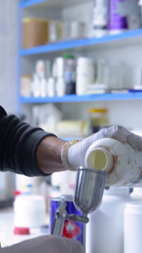 Un addetto con guanti versa la miscela liquida nel serbatoio della pistola a spruzzo
