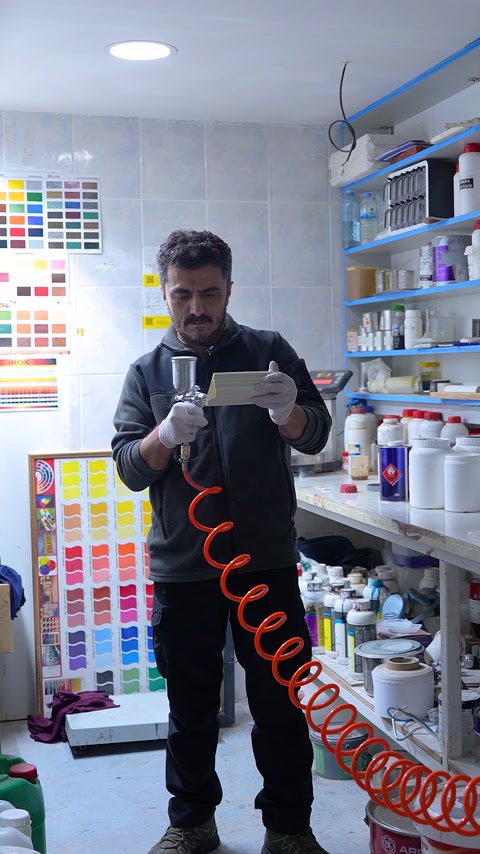 Un addetto del laboratorio prepara con attenzione l'attrezzatura di spruzzatura prima dell'applicazione