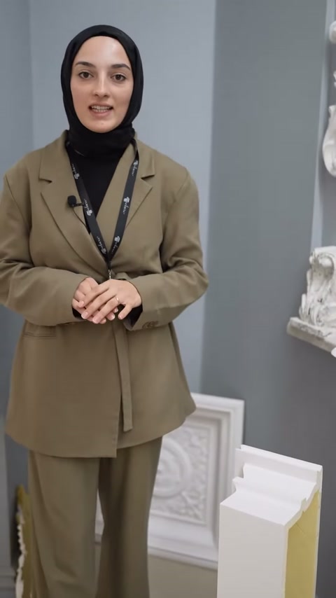 Sunucu gri duvar önünde poliüretan dekorasyon ürünlerini açıklıyor.