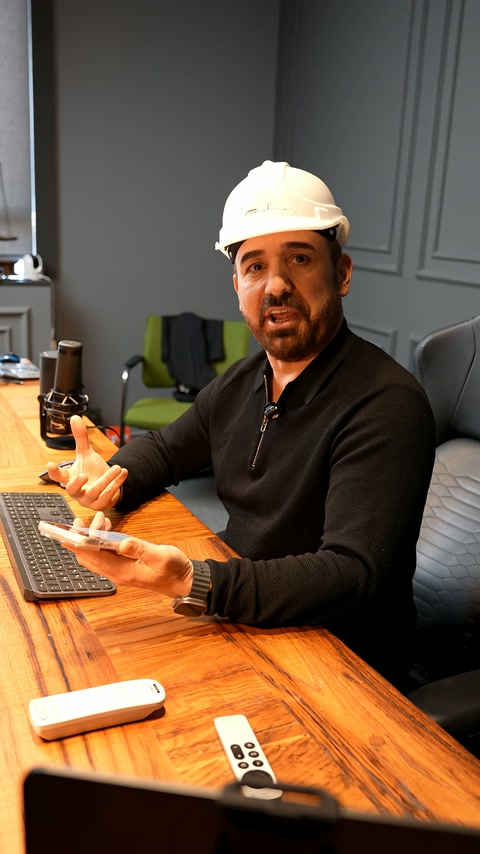 A presenter in a beret discusses design while showing a phone in hand.