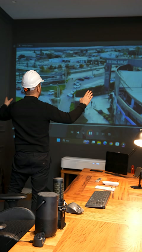 An expert examines aerial imagery and project data on a large screen.