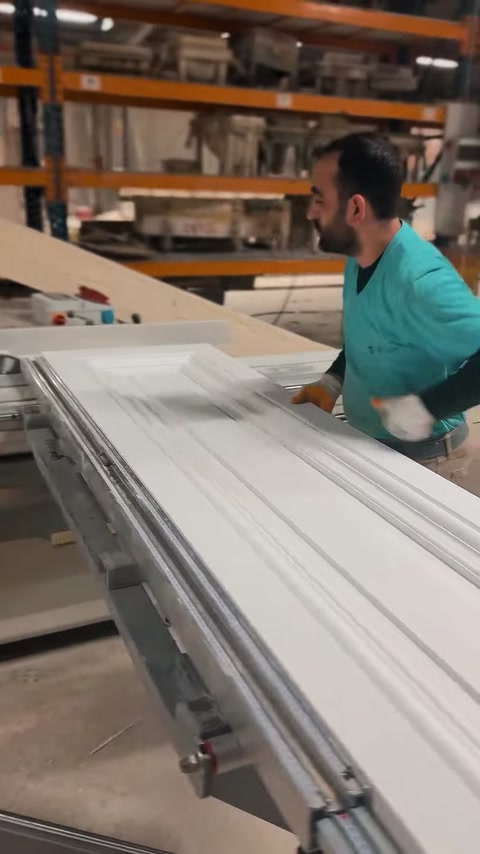 Operaio che fa scorrere controllato un profilo per cornice sulla tavola di produzione