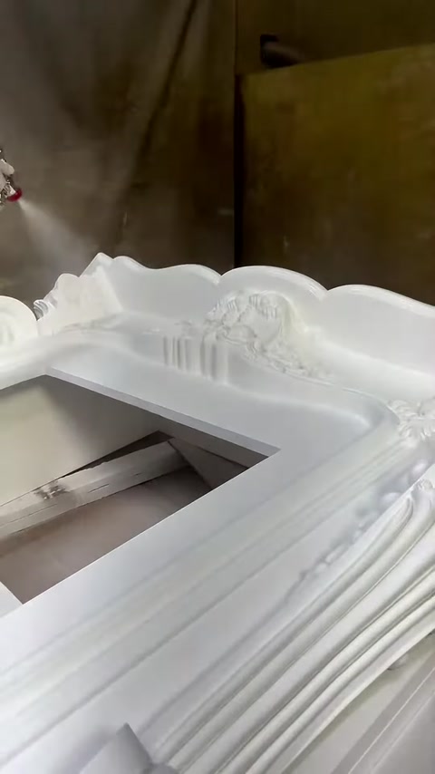 Gli ornamenti curvi della parte superiore della cornice bianca del camino sono mostrati da vicino