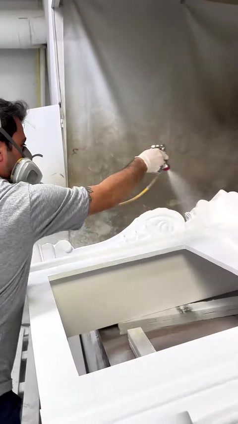 Un operatore con maschera protettiva vernicia la superficie del camino con una pistola a spruzzo
