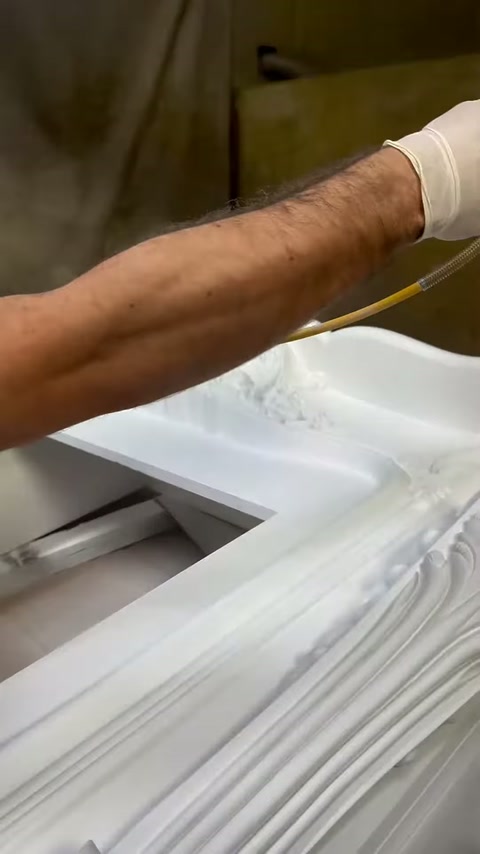 L'operaio con guanti spruzza vernice uniformemente sulla superficie in rilievo del camino