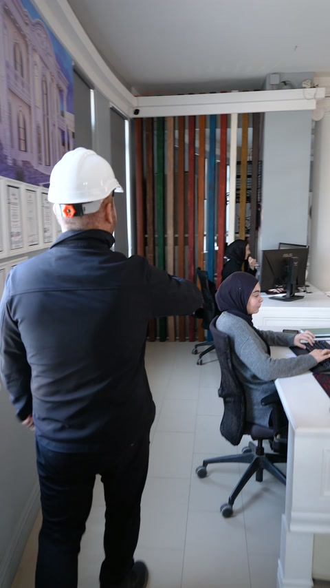 Baretli görevli dekoratif örneklerin bulunduğu ofis bölümünde ilerliyor