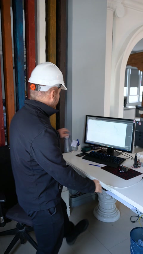 Çalışan kemerli dekoratif detaylarla çevrili çalışma masasına yaklaşıyor