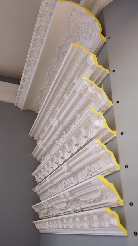 Cornici decorative per soffitto, valorizzate da luce gialla calda, sono visibili una accanto all'altra.